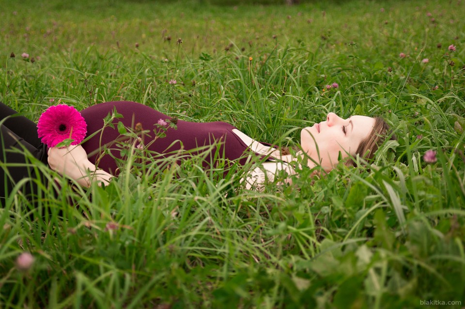 Happy pregnant woman lying in grass
